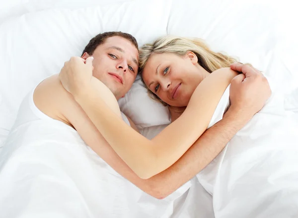 Casal deitado na cama e sorrindo para a câmera — Fotografia de Stock