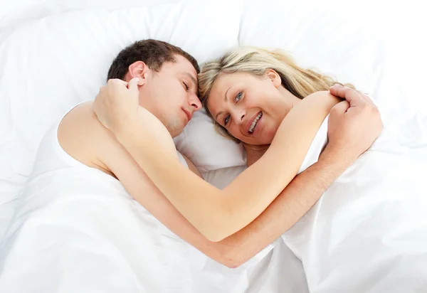 Donna sdraiata a letto con un ragazzo che sorride alla telecamera — Foto Stock