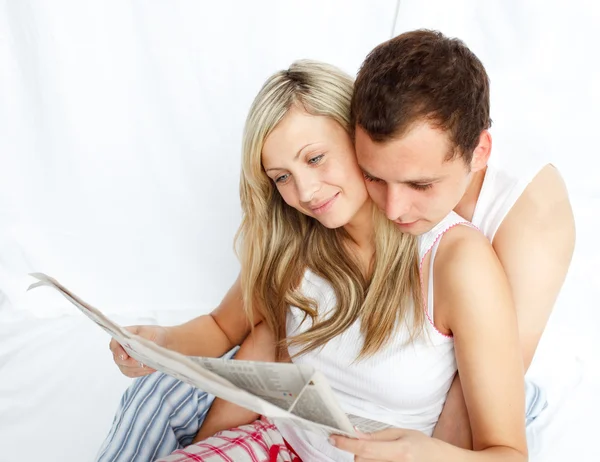 Casal lendo um jornal na cama — Fotografia de Stock
