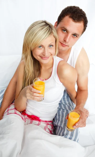 Casal beber suco de laranja na cama — Fotografia de Stock