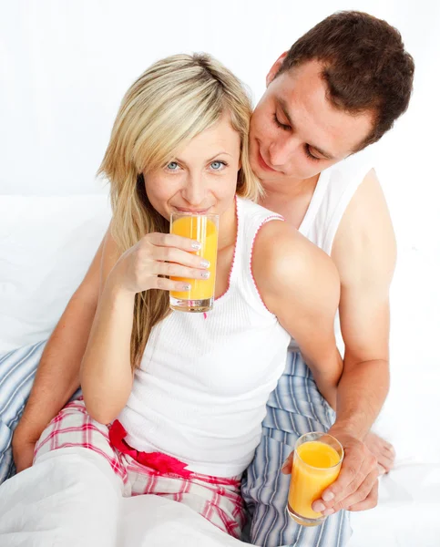 Ζευγάρι πίνοντας χυμό πορτοκαλιού στο κρεβάτι — Φωτογραφία Αρχείου