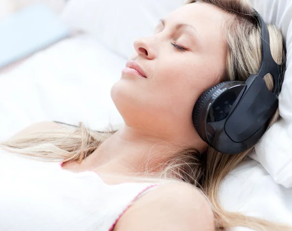 Ελκυστική γυναίκα με τα ακουστικά για ύπνο σε ένα κρεβάτι — Φωτογραφία Αρχείου