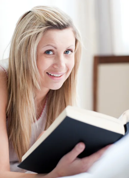 Mulher alegre lendo um livro deitado em sua cama — Fotografia de Stock
