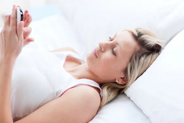 Сконцентрированная женщина отправляет сообщение лежащее на кровати — стоковое фото
