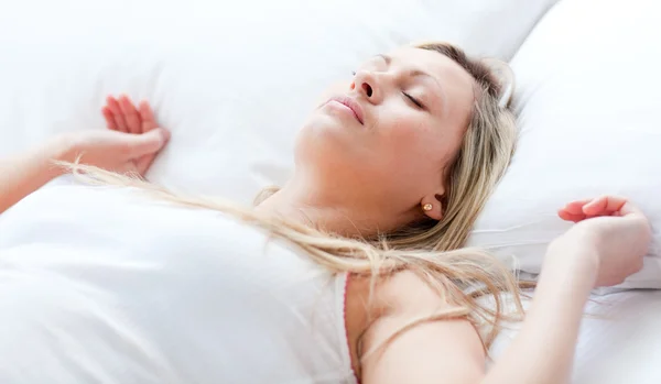 Mujer joven y relajada durmiendo en una cama —  Fotos de Stock