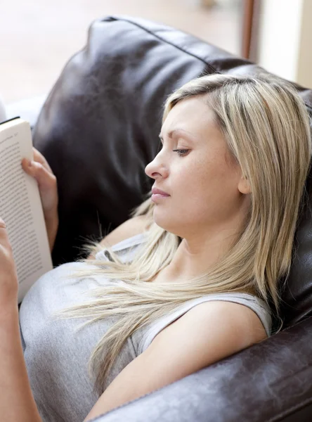 Kadın kanepede oturan bir kitap okuma konsantre — Stok fotoğraf