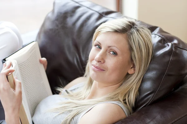 Очаровательная женщина читает книгу, сидя на диване — стоковое фото