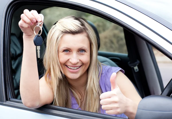 Charming female driver showing a key after bying a new car — Stock Photo, Image