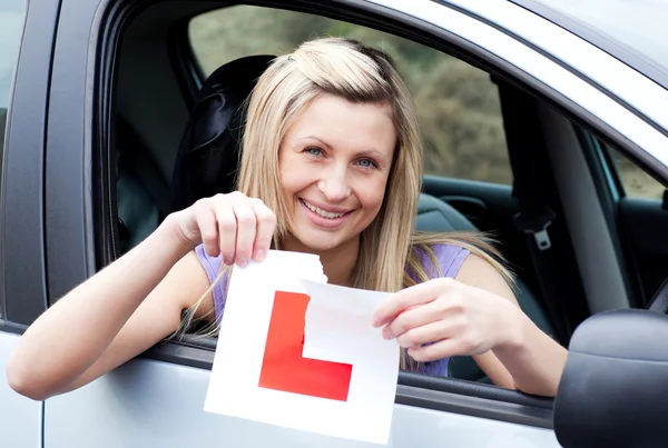 Cheerful young female driver tearing up her L sign — Stock Photo, Image