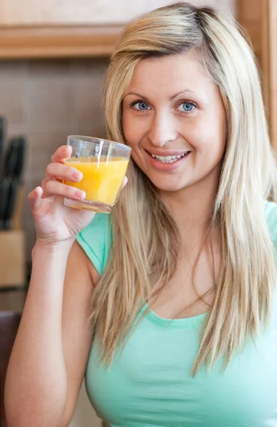 Ενθουσιώδεις γυναίκα πίνοντας χυμό πορτοκαλιού σε μια κουζίνα — Φωτογραφία Αρχείου