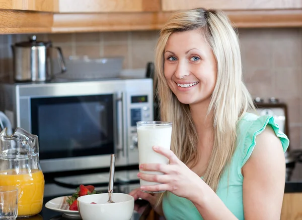 Mulher sorridente tomando um café da manhã saudável em uma cozinha — Fotografia de Stock