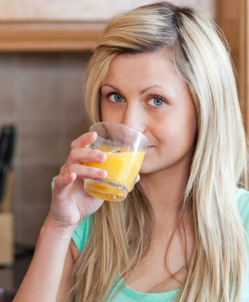 Mulher encantadora bebendo suco de laranja em uma cozinha — Fotografia de Stock