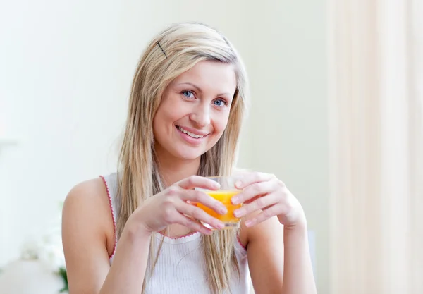 Retrato de uma mulher alegre bebendo um suco de laranja — Fotografia de Stock