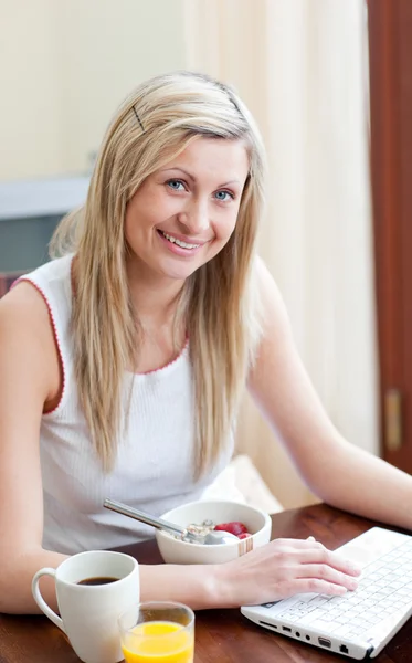 Charmig kvinna använder en bärbar dator samtidigt ha en frukost — Stockfoto
