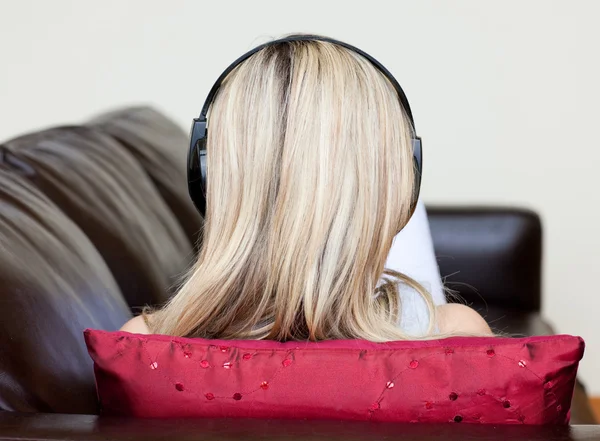 Blond kobieta z słuchawkami na leżące na kanapie — Zdjęcie stockowe