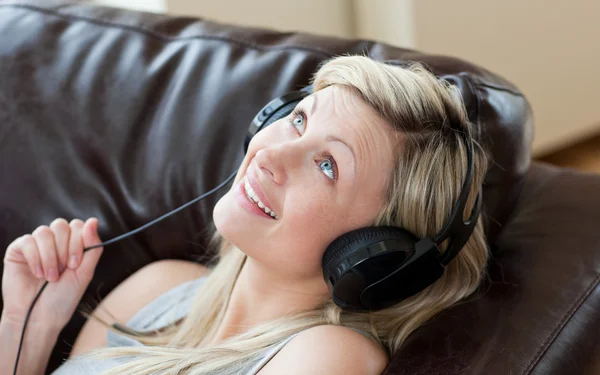 Joyful woman with headphones on lying on a sofa — Stock Photo, Image