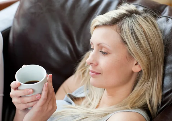 リラックスした女性は、ソファに座ってコーヒーを飲む — ストック写真