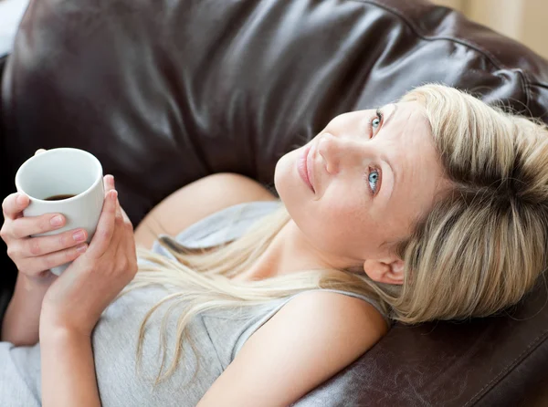 Okouzlující žena pití kávy sedí na pohovce — Stock fotografie