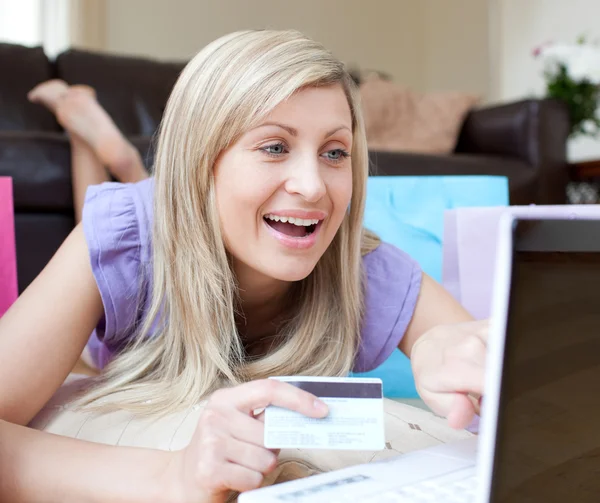 Mujer feliz de compras en línea acostado en el suelo — Foto de Stock