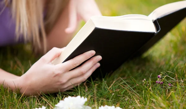 Närbild av en kvinna som läser en bok i en park — Stockfoto