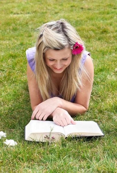 Νεαρή γυναίκα διαβάζοντας ένα βιβλίο σε ένα πάρκο — Φωτογραφία Αρχείου
