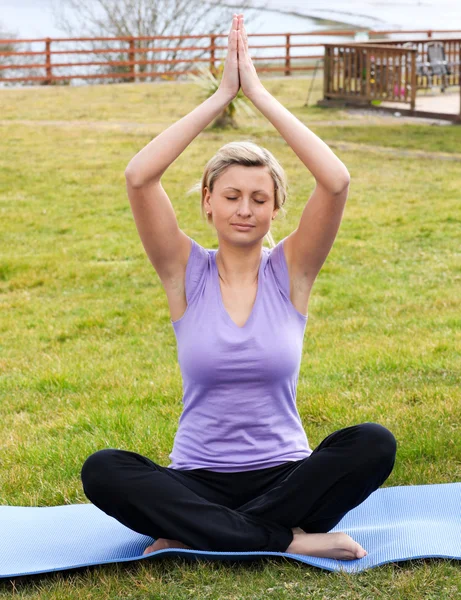 Ontspannen vrouw doen yoga zittend op het gras — Stockfoto