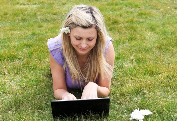 Charmante jonge vrouw met behulp van een laptop in een park — Stockfoto