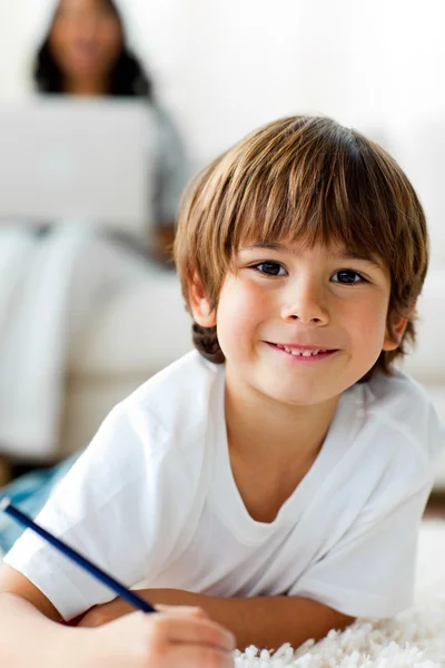 Glimlachend kleine jongen tekening liggend op de vloer — Stockfoto