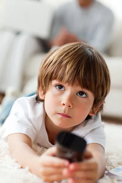Concentrated little boy watching TV lying on the floor — Stock Photo, Image