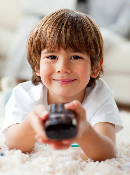 Smiling little boy watching TV lying on the floor — Stock Photo, Image