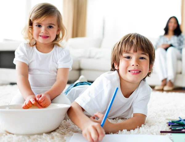 Cheerful siblings eating chips and drawing — Stock Photo, Image