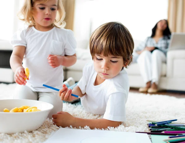 Adorable children eating chips and drawing — Stock Photo, Image