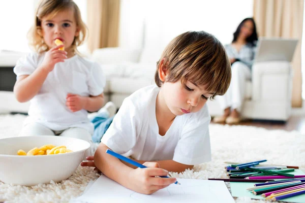 Cute little gir eating chips and her brother drawing — Stock Photo, Image