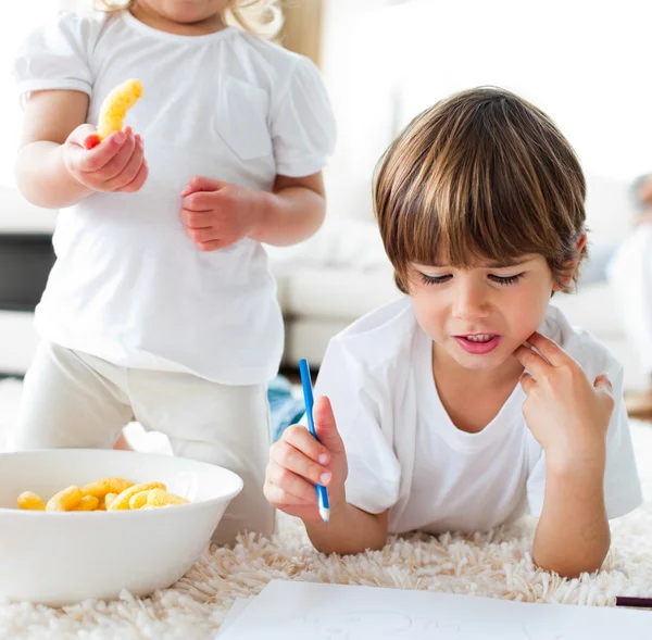 Close-up of children eating chips and drawing — Stock Photo, Image