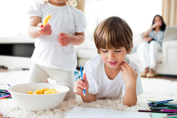 Close-up of siblings eating chips and drawing — Stock Photo, Image