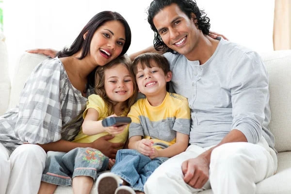 Счастливая семья смотрит телевизор вместе сидя — стоковое фото