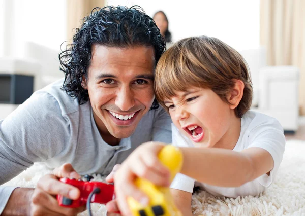 Upphetsad liten pojke och hans far spela videospel liggande på t — Stockfoto