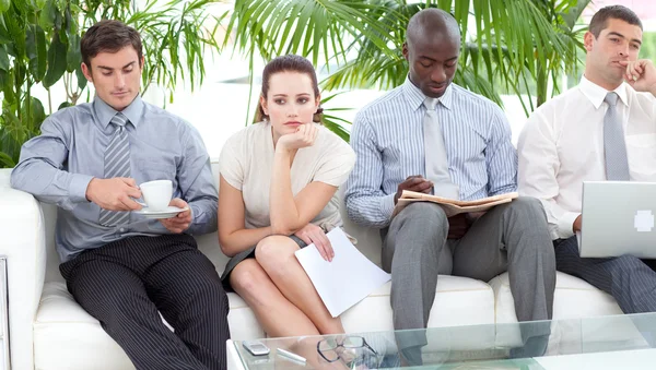 Gelangweilte Geschäftsleute sitzen auf einem Sofa und warten auf ein Interview — Stockfoto