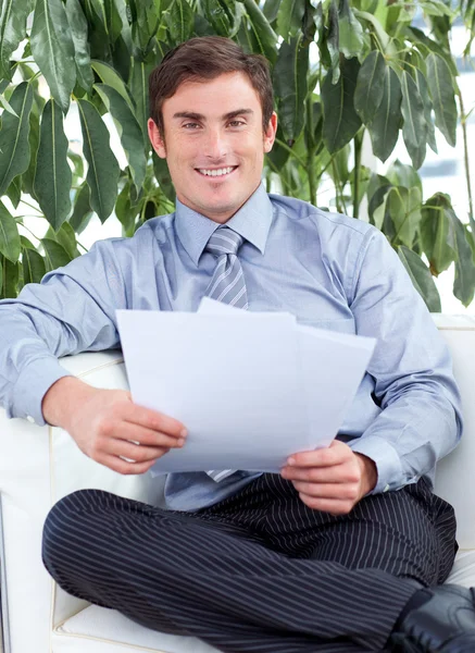 Geschäftsmann liest Zeitung und lächelt in die Kamera — Stockfoto