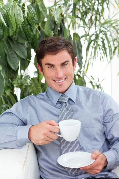 Бизнесмен пьет чашку кофе на диване — стоковое фото