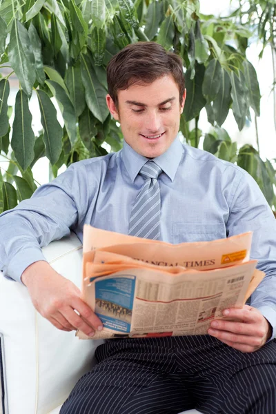 Empresário atraente lendo um jornal em um sofá — Fotografia de Stock