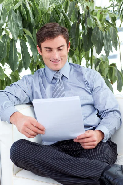 Tevreden zakenman lezen van documenten op een sofa — Stockfoto