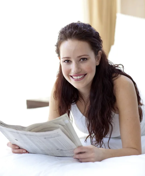 Beautiful woman in bed reading a newspaper — Stock Photo, Image