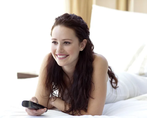 Beautiful woman watching television in bedroom — Stock Photo, Image