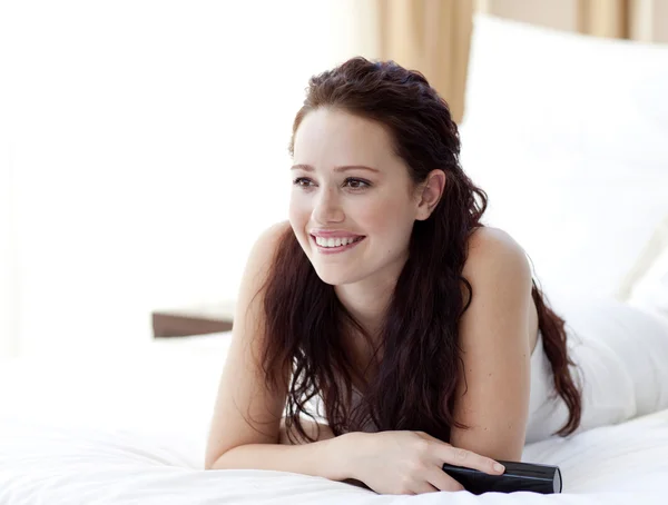 Beautiful woman lying in bed watching television — Stock Photo, Image