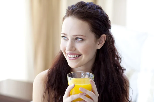 Жінка п'є апельсиновий сік у спальні — стокове фото