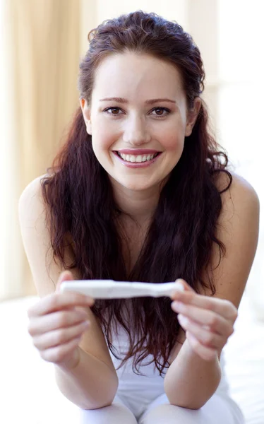 Leende kvinna håller ett graviditetstest — Stockfoto