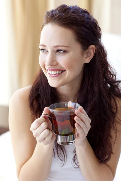 Красивая женщина пьет чашку чая в постели — стоковое фото