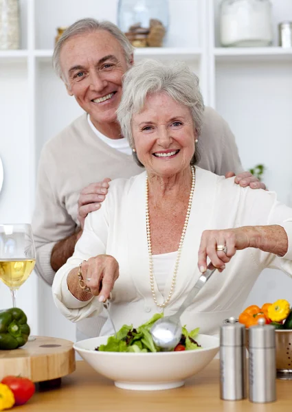 Heureux couple de personnes âgées mangeant une salade dans la cuisine — Photo