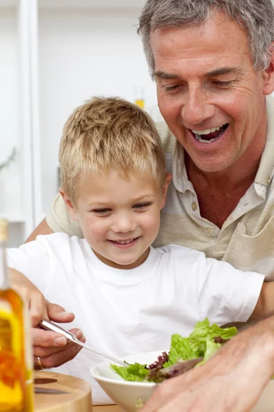 Happy grandfather eating a salad with grandson — Stock Photo, Image